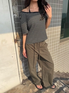 Detail of olive green wide-leg cargo pants with adjustable drawstring waist and relaxed fit