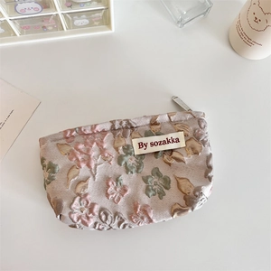 Macro detail of French floral embossed jacquard fabric on a portable cosmetic pouch