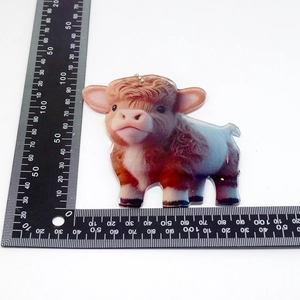 Detail of cartoon highland cow acrylic charm with metal chain on a white background