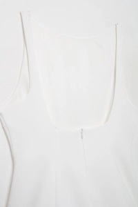 Detail view of the back neckline and hidden zipper of a white pleated women dress
