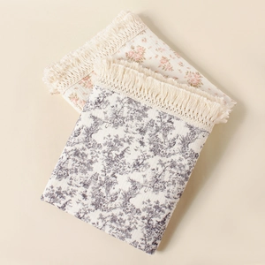 Detail of floral cotton baby blanket with fringe tassels and soft muslin texture