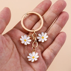 Sweet daisy flower keychain with three white enamel pendants and a golden metal ring