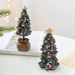 Mini resin Christmas tree figurines with golden stars and festive ornaments on table