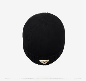 Top-down view of black ribbed knit beanie with plush texture and triangular leather patch
