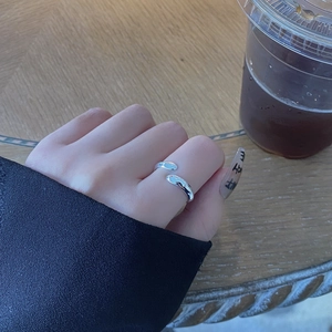 Detail of adjustable silver ring with water drop wrap design worn in a lifestyle setting