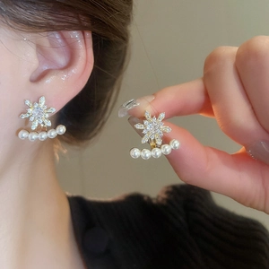 Close-up of snowflake stud earrings with sparkling zircons and delicate pearl fringe