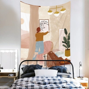 Artistic bohemian wall tapestry detail showing a woman hanging prints in warm tones