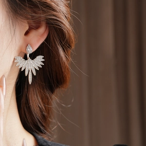 Close-up of elegant silver wing earrings with cubic zirconia worn by a model