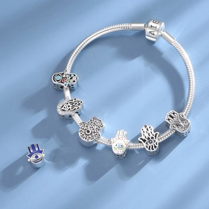Detail of silver S925 snake chain bracelet with Hamsa Hand charms and blue enamel eye beads