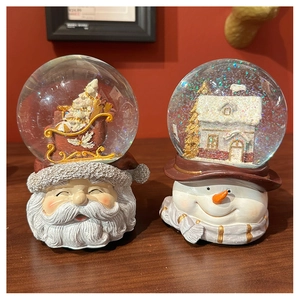 Detailed view of resin bases featuring Santa and Snowman in glass Christmas snow globes