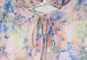 Detailed close-up of the delicate floral pattern and crisscross strap design on the dress