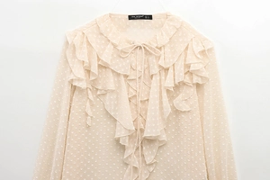 Detailed macro shot of apricot Swiss dot chiffon shirt with layered ruffles and neck tie