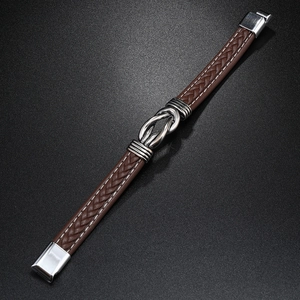 Detail of a brown braided leather bracelet with a silver infinity symbol magnet clasp