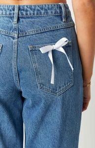 Detail of high waisted straight leg jeans with white satin bow on the back pocket