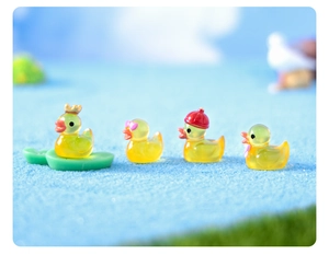 Miniature resin luminous ducks with crown and bow on a macro landscape base