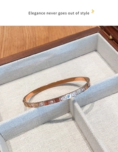Detail of rose gold bangle with square zircon settings in a white jewelry box