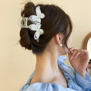 Detailed view of hair claw clip with white lace butterfly and pearl on elegant hairstyle