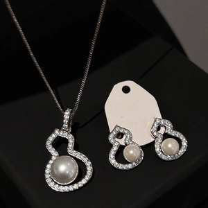 Detailed view of silver gourd jewelry set with zircon and pearls in a black display case