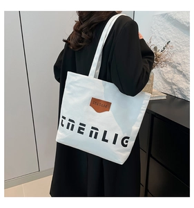 Lifestyle shot of large canvas tote bag with black lettering and leather patch detail