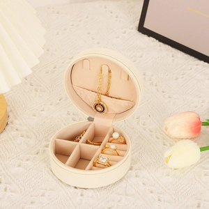 Macro detail of round cream PU leather jewelry box showing necklace hooks and ring slots