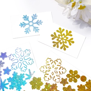 Macro detail of gold and blue glitter snowflake stickers on a clean white background