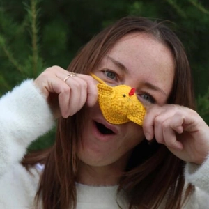 Close-up of handmade crochet yellow chicken nose warmer with a red comb and beak