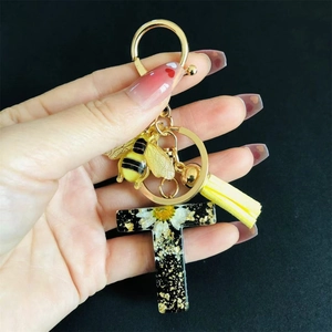 Detail of letter T resin keychain with real daisy flowers gold foil and bee charm