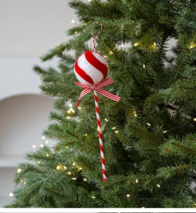 Detail of red and white striped lollipop Christmas ornament hanging on a festive tree