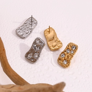 Macro shot of gold and silver geometric earrings with sparkling diamonds and water droplets