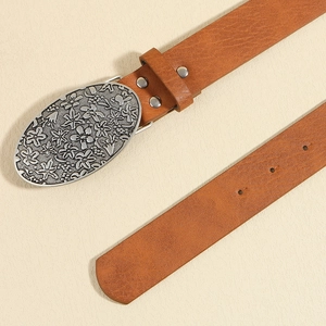 Detail of vintage brown leather belt featuring an ornate floral engraved alloy buckle