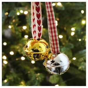 Detailed view of champagne metal bells with star cutouts and red heart ribbon ornaments