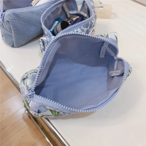 Detail of light blue corduroy and floral fabric makeup bags with zippers and lavender lining