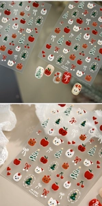 Macro detail of Christmas nail stickers with festive cat, apple, and tree motifs