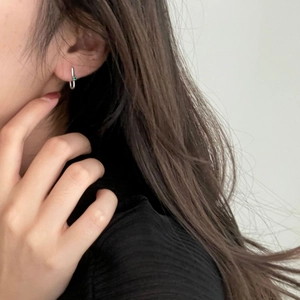 Close-up of 925 sterling silver hoop earring with green zircon on woman's ear