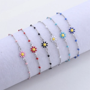 Detailed view of colorful enamel daisy charms on delicate 18K gold bead chain bracelets