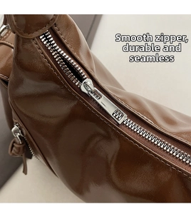 Detail of smooth silver metal zipper on premium brown glossy leather crossbody bag