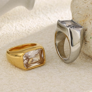Macro shot of gold and silver square-cut zircon rings on a textured stone surface
