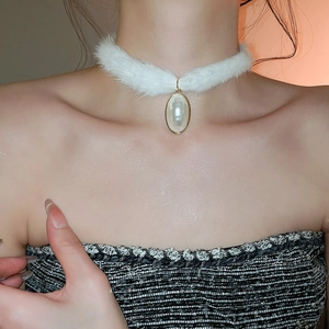 Detail of plush white faux fur choker featuring an elegant gold-rimmed pearl pendant