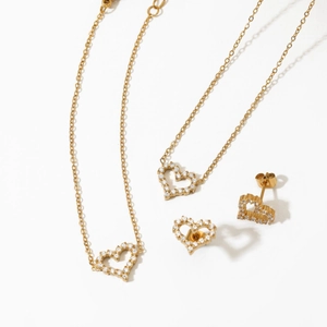 Golden heart necklace and earrings set with sparkling stones on white background