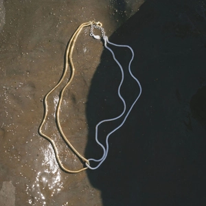 Two-tone 18k gold and silver stainless steel flat snake chain necklace on sand