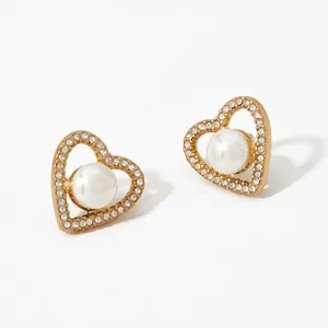 Detailed macro view of heart-shaped gold earrings with sparkling crystals and white pearls