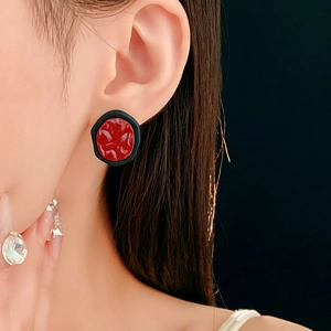 Détail rapproché de boucles d'oreilles rétro rondes avec centre rouge et bord noir mat