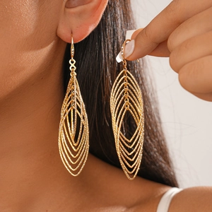Detail of gold oval geometric drop earrings with zircon accents on a model profile
