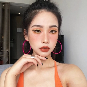 Détail d'un mannequin portant de grandes créoles roses avec une finition gomme mate
