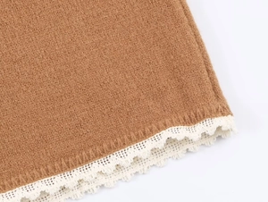 Détail du tissu en maille marron avec une bordure en dentelle écrue délicate