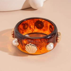 Detail of amber resin bangle with inlaid golden seashells and white faux pearls