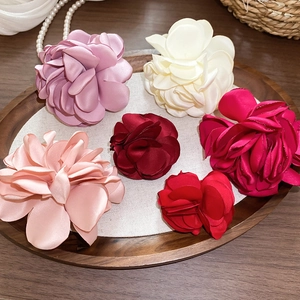 Nahaufnahme von handgefertigten Stoffblumenringen in eleganten Farben auf einem Holztablett