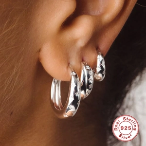 Three S925 sterling silver hoop earrings with star patterns shown on a female ear model