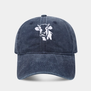 Close-up of a dark blue washed denim baseball cap with white cow head embroidery