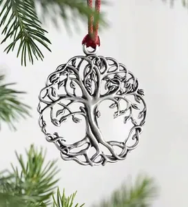 Silver Tree of Life ornament with red silk cord hanging on natural green pine branches
